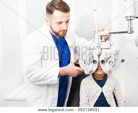 Optometrist Doctor Checks The Young Girls Eyesight. If The Girl Has Poor Eyesight, The Doctor Will G