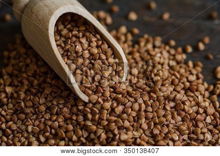 Scoop And Buckwheat Macro View On Rustic Background. Close Up Raw Buckwheat Background.