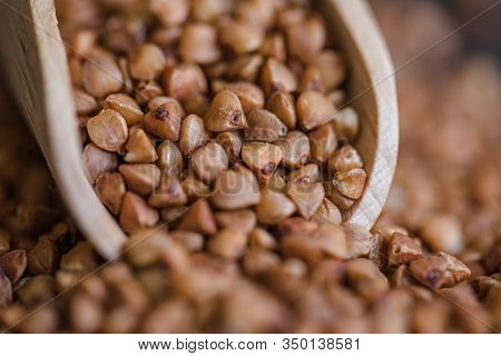 Scoop And Buckwheat Macro View On Rustic Background. Close Up Raw Buckwheat Background.