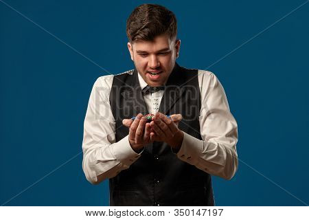 Noob In Poker, In Black Vest And White Shirt. Holding Some Colored Chips. Posing Against Blue Backgr