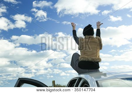 Woman With Back And Wool Cap Sitting On Top Of Car