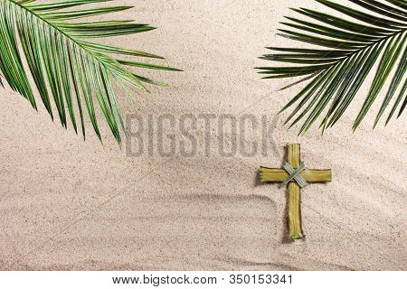 Cross And Palm Tree Leaves On Sand. Palm Sunday Concept. Top View