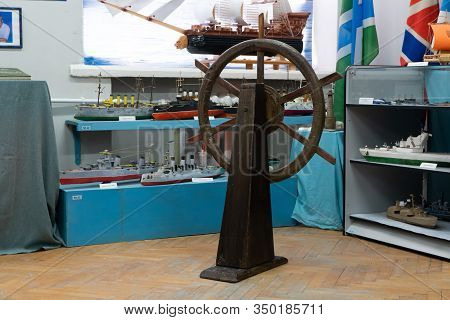 Sukhoy Log, Russia - June 26, 2019: A Helm Wheel Of A Real-scale Model Ship And Miniature Model Of S