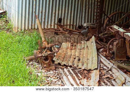 Old Rusted Farm Machinery From A Bygone Era Lying As Rubbish Under An Old Shed