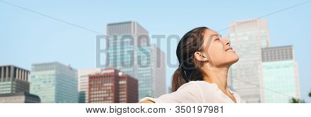 Happy healthy woman taking deep breath in city clean air for pollution concept panoramic lansdcape header banner. Asian lady in Asia face portrait with closed eyes.