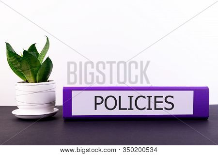 Policies Office Folder Lies On A Dark Table With A Flowerpot And A Flower On A Light Background