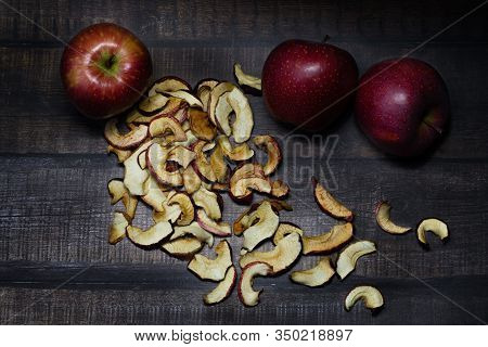 Dried Apple Chips And Three Red Apples On A Brown Wooden Table. Organic Natural Food. Close Up. Top 