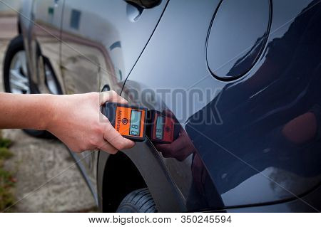 Measuring The Thickness Of The Car Paint Coating In Black Color Using A Paint Thickness Gauge.