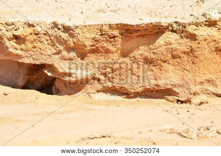 Background Of Yellow Sand With Small Stones After Rain. Soil Erosion After Heavy Rainfall And Precip