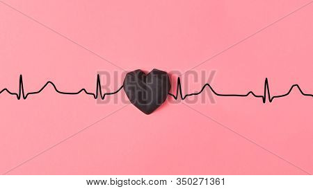 Congratulation card with gypsum hearts black color on a line of echocardiogram love line on a pastel pink background, copy space. Valentine's day greeting card.
