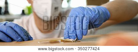 Close-up Of Male Hands Varnish Over Wooden Furniture. Man In Blue Gloves And Respirator Smearing Woo