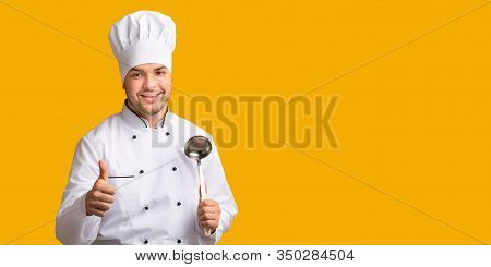 Professional Chef Guy Holding Ladle Spoon Gesturing Thumbs-up Posing On Yellow Studio Background. I 