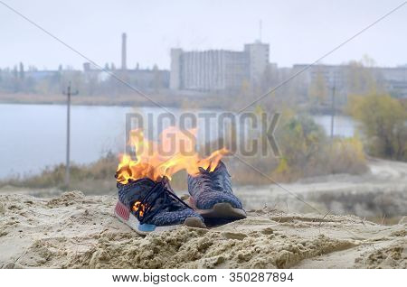 Burning Sports Sneakers Or Gym Shoes On Fire Stand On Sandy Beach Coast. Athlete Burned Out. Physica