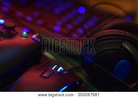 Modern Gamepad And Gaming Mouse Lies With Keyboard And Headphones On Table In Dark Playroom Scene. V