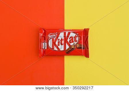Kit Kat Chocolate Bars In Red Wrapping Lies On Yellow And Red Background. Kit Kat Created By Rowntre