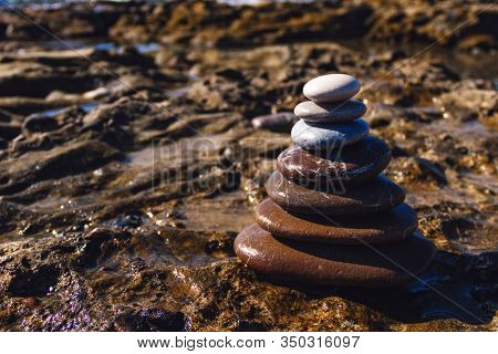 Pyramid Of Stones For Meditation, Lying On The Sea Coast At Sunset. Pyramid Of Stones On The Beach.