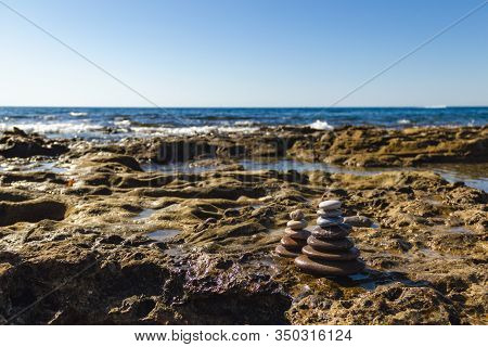 Pyramids Of Stones For Meditation Lying On Sea Coast. Stack Of Stones Against Blurred Seascape, Spac