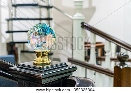 Faceted Glass Ball With Multi-colored Highlights Is Mounted On A Wooden Staircase.