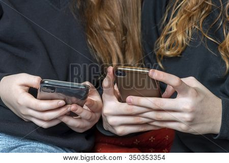 Teenage Girls Being Cyber Bullies  Or Just Catching Up On Social Media Both On There Phones, Hand Le