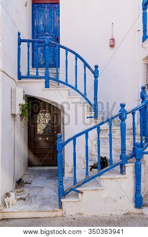 3 Cats Laying Down On Stairs With Blue Railing In Front Of A Traditional Greek House In Skala Eresso
