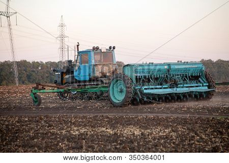 Agricultural Mechanical Seeders Of Grain Crops. Tactor With A Seeder Sows Grain In The Field. A Farm