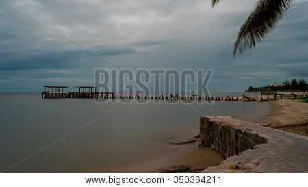 Palm Tree And  Walkeway In Front Of Dilapidated Old Fishing Dock Collapsing Into The Sea In Pak Nam 