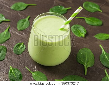 A Glass With The Smoothie And Scatter The Spinach Leaves On A Stone Background. Fitness Product. Die