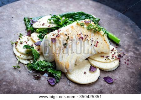 Gourmet fried European skrei cod fish filet with rapini broccoli rabe and creoxetti pasta as closeup on a modern design plate 