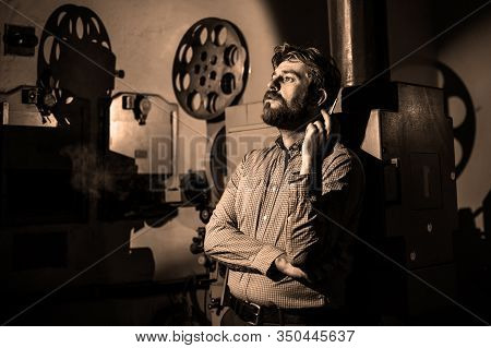 Beautiful Hipster Man Standing Near A Film Projector In The Room Projectionist