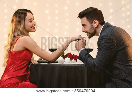 Gallant Man Kissing Hand Of His Pleased Girfriend On Romantic Date In Restaurant