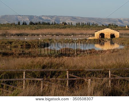 A Ruined Building Reflecting Into The Water With Birds On Top Of It