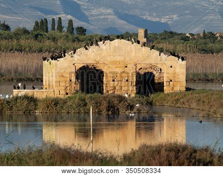 A Ruined Building Reflecting Into The Water With Birds On Top Of It