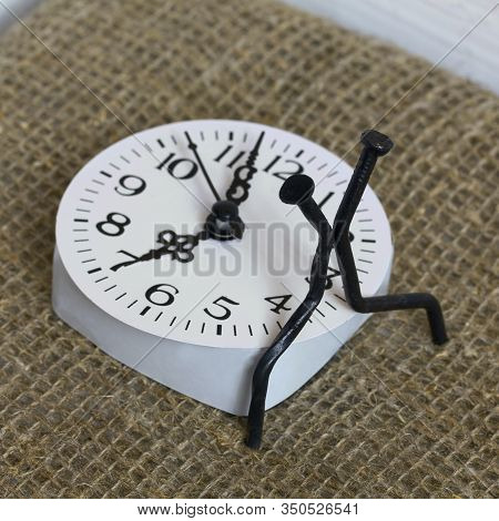 Figurines Of Man Made From Carpentry Nails. Sit On The Watch Dial Back To Back. Symbol Of The Inexor