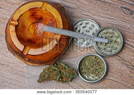 Close Up Of Cannabis - Marijuana Bud And Accessories - Grinder, Wooden Ashtray, Rolling Paper And Ro