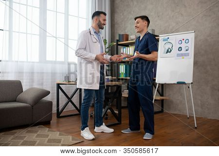 Two Doctors Talking During Changeover And Looking Positive
