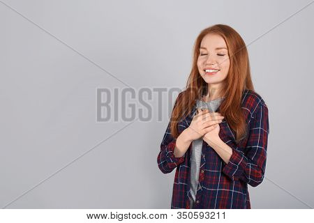 Beautiful Grateful Woman With Hands On Chest Against Light Grey Background. Space For Text
