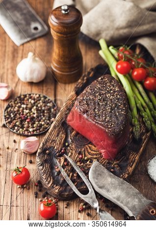Slice Of Raw Beef Topside Joint With Salt And Pepper On Wooden Chopping Board With Fork And Knife, A