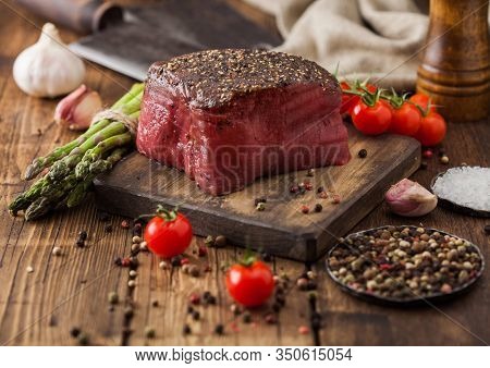Slice Of Raw Beef Topside Joint With Salt And Pepper On Wooden Chopping Board With Tomatoes Garlic A