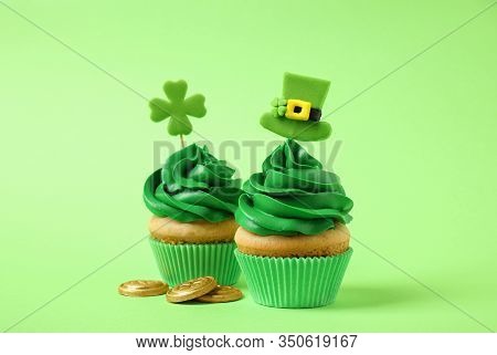 Delicious Decorated Cupcakes And Coins On Light Green Background. St. Patrick's Day Celebration