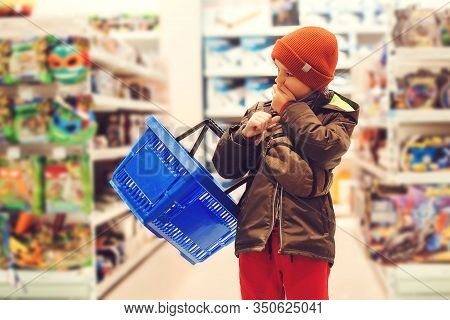 Little Kid Holding Shopping Cart In Kids Store. Boy Choosing Toy In Big Assortement In Supermarket. 