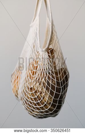 Different Buns Of Fresh Bread In Wicker String Bag On Gray Background. Freshly Baked Wheat Bread, St