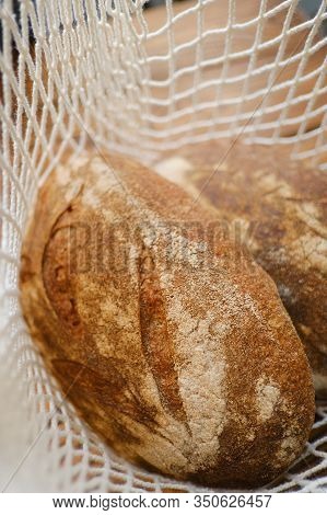 Different Buns Of Fresh Bread In Wicker String Bag. Freshly Baked Wheat Bread, Still Life With Bread