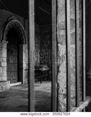 Black And White Vertical Photo Of The Door Of A Medieval Stone Building With Columns And Iron Bars I