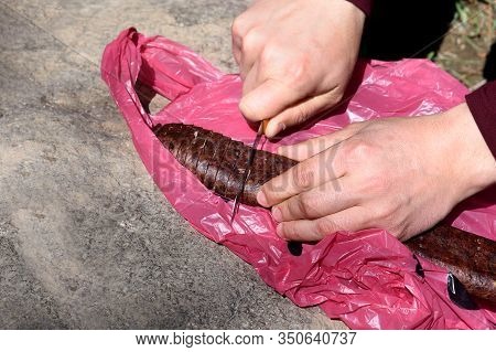 Mens Hands Cut Sujuk On Used Plastic Bag For Snack On Stone