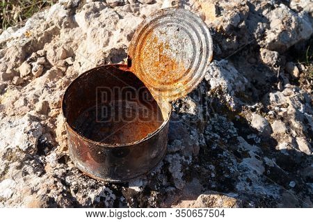 Open Old Rusty Tin Can Covered With Ash On Stone At Sunny Day. Concept Of Environmental Pollution, E