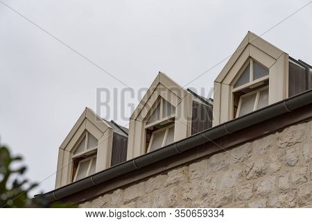 Roof With Three Beautiful White Dormer Windows. Ancient Round Dormer Windows In Rooftop. Symmetrical