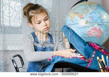 School Girl Packing Books In Backpack At The Table For School After Finishing Homework, Back To Scho