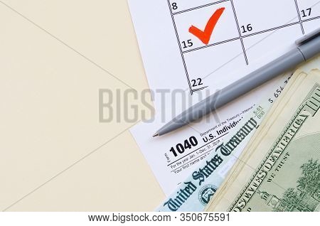 1040 Individual Income Tax Return Form With Refund Check And Hundred Dollar Bills On Calendar With M