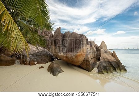 Tropical Beach At Curieuse Island Seychelles With Famous Volcanic Stones And Palm Tree Leafs. Nobody