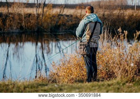 A Man Fisherman Fishing In The River With A Fishing Rod